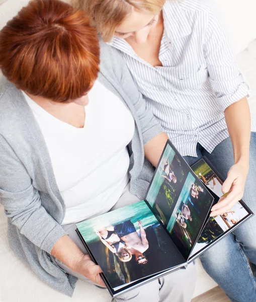 Mãe e filha procurando livro de fotos — Fotografia de Stock