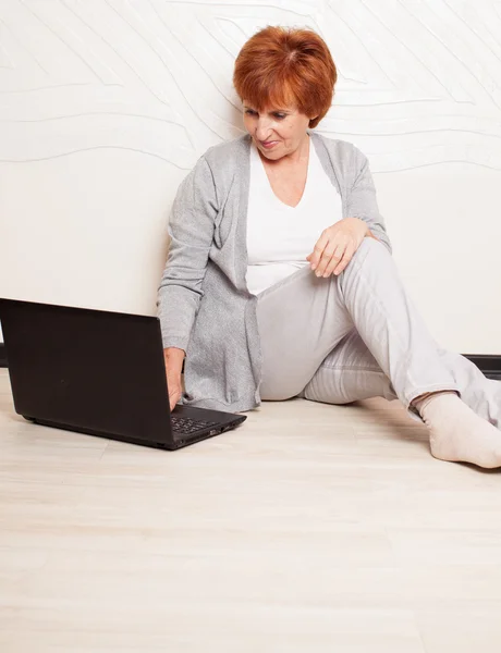 Vrouw zittend op de vloer met laptop — Stockfoto