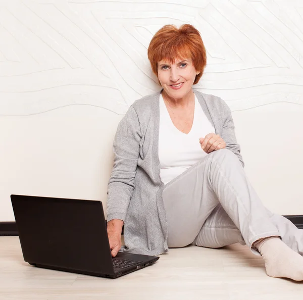 Vrouw zittend op de vloer met laptop — Stockfoto