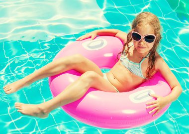 Yüzme havuzunda şişme yüzük takan kız.