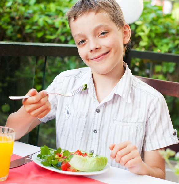 Criança comendo salada em um café — Fotografia de Stock