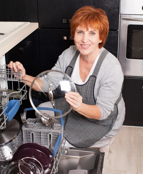 Frau faltet das Geschirr in der Spülmaschine — Stockfoto