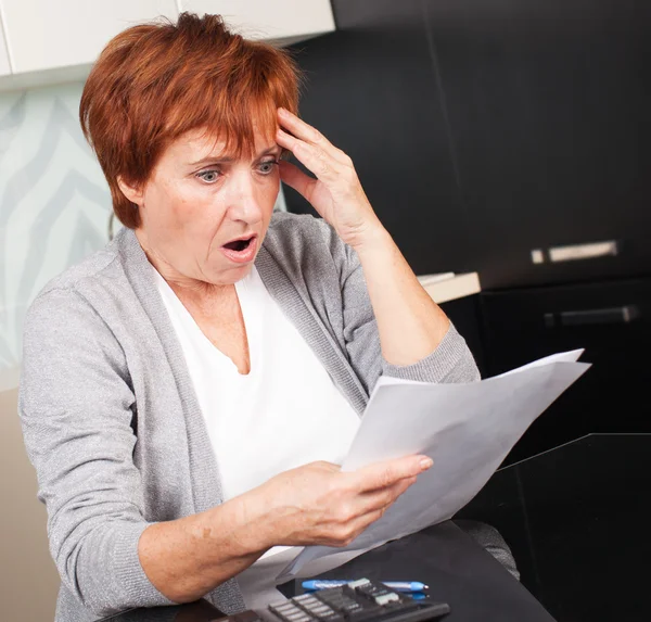 Oudere vrouw sorteren door middel van haar oude ontvangsten — Stockfoto