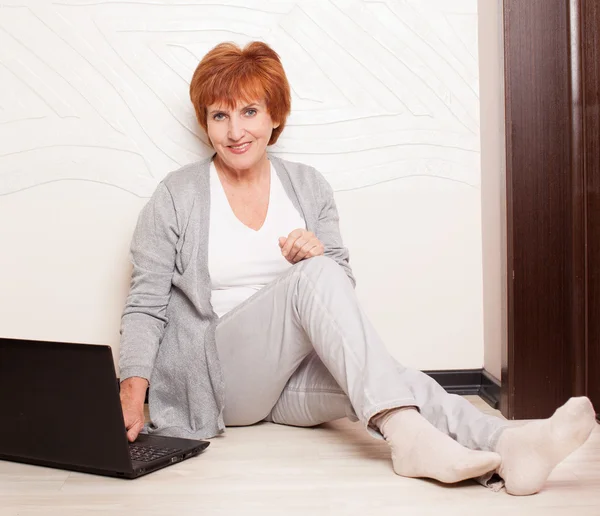 Vrouw zittend op de vloer met laptop — Stockfoto