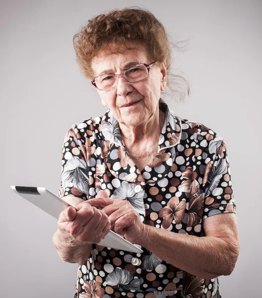 Old woman holding a tablet in the hands of — Stock Photo, Image