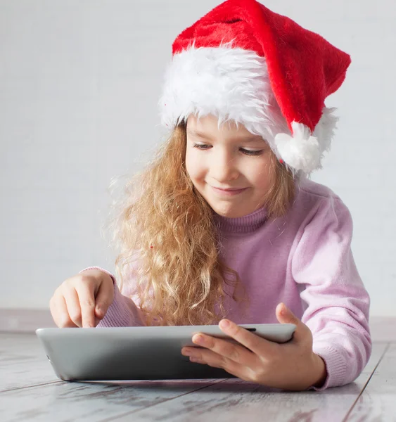 Child in christmas hat with tablet — Stock Photo, Image