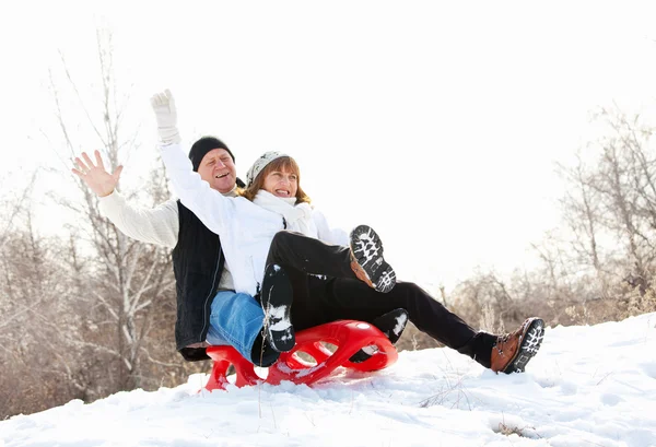 Mature couple sledding — Stock Photo, Image