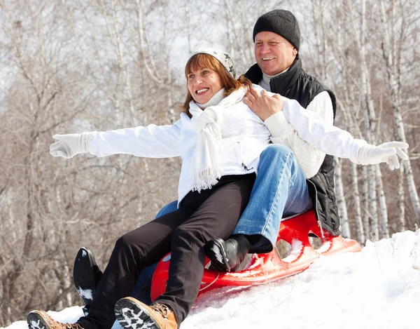 Mature couple sledding — Stock Photo, Image