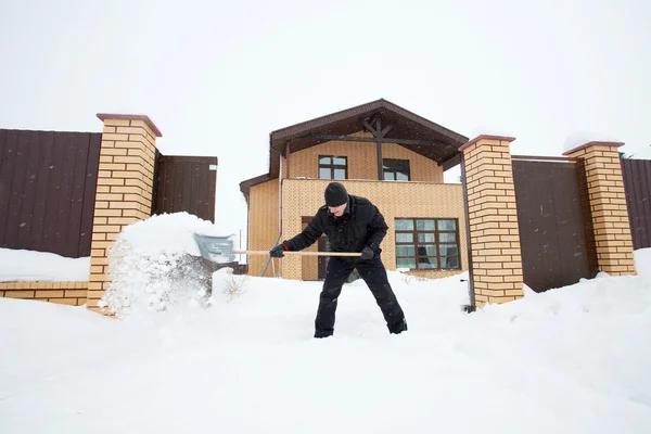 El hombre limpia la nieve paleando — Foto de Stock