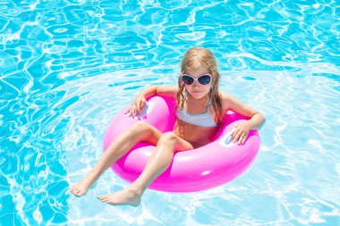 Yüzme havuzunda şişme yüzük takan kız.