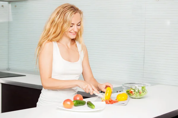 Ung kvinna förbereder grönsakssallad — Stockfoto