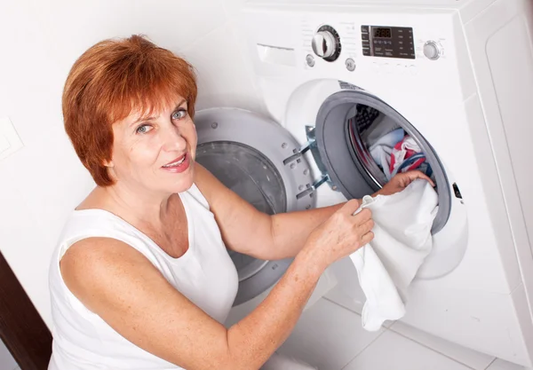 Mulher coloca roupas na máquina de lavar roupa — Fotografia de Stock