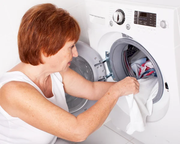 Kadın çamaşır makinesine çamaşır koyuyor. — Stok fotoğraf