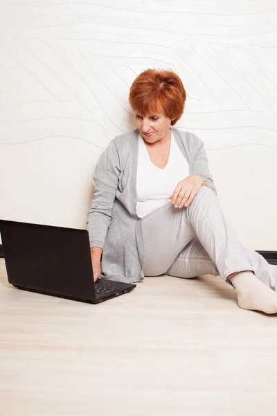 Vrouw zittend op de vloer met laptop — Stockfoto