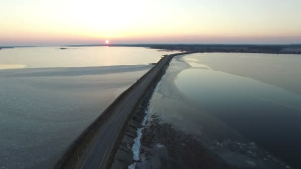 4K. Vuelo sobre la carretera en el agua a principios de primavera en la puesta del sol, vista aérea . — Vídeos de Stock