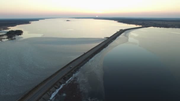 4K. Vue aérienne de la route dans l'eau avec des voitures en mouvement au coucher du soleil, vue de dessus au début du printemps . — Video
