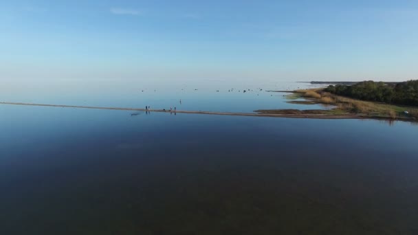 4K. Vuelo sobre el mar y la gente feliz al atardecer, vacaciones con la familia, las niñas en la piedra de pie en el agua, vista panorámica aérea . — Vídeos de Stock