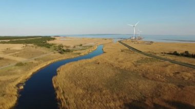 mavi nehir ve rüzgar türbinleri doğru alanları üzerinde 4 k. yüksek uçuş ve deniz günbatımı hava panoramik manzaraya.