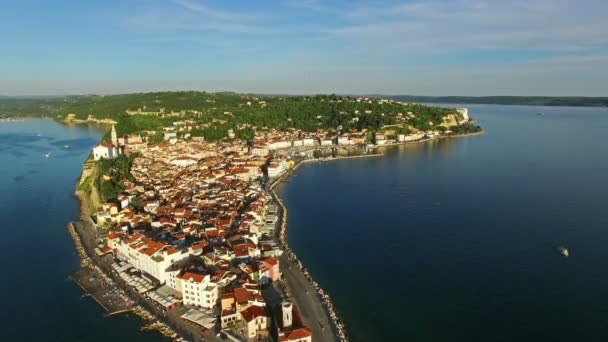 Voo sobre a cidade velha Piran, vista panorâmica aérea com casas antigas, telhados, Igreja Paroquial de São Jorge, fortaleza e mar. Eslovénia . — Vídeo de Stock