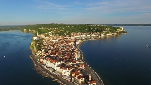 Flight over old city Piran, aerial panoramic view with St. George 's Parish Church, old houses, roofs, fortress and the sea. Словения . — стоковое видео