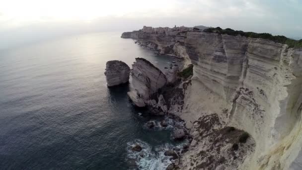 Flight and takeoff over Bonifacio bay area at sunset colors. Rocks and sea. Corsica, France. Aerial panoramic view. — Stock Video