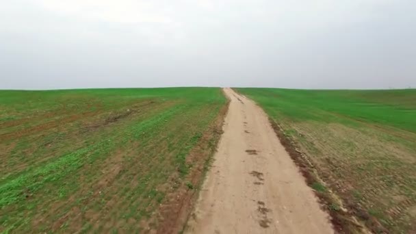 4K. Vol et décollage au-dessus de champs verts avec route de terre, vue panoramique aérienne . — Video