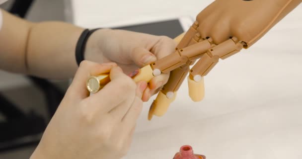 Mujer está pintando uñas esmalte de uñas rosa en la mano de la prótesis, manos vista de cerca. — Vídeos de Stock