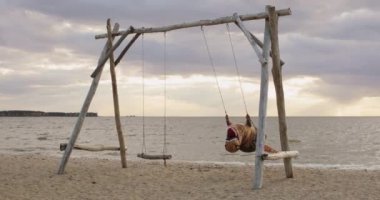 İnanılmaz büyüklükte şişme dinozor gün batımında deniz sahilinde sallanıyor..