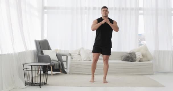Sportif genç adam evdeki oturma odasında zıplama egzersizi yapıyor.. — Stok video
