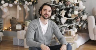 Genç mutlu adam evde Noel ağacının yanında duran hediye kutusunu açıyor..