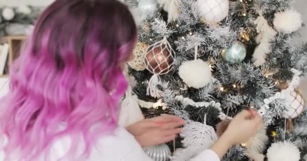 Γυναίκα με ροζ τρίχες διακοσμεί μπάλες χριστουγεννιάτικο δέντρο, γιρλάντες και pompons. — Αρχείο Βίντεο