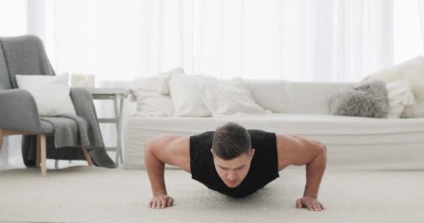 Atletische man doet push-ups oefeningen op training thuis tijdens lockdown. — Stockvideo