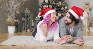 Noel Baba 'nın kırmızı şapkalı mutlu çift Noel ağacının yanında yatıyor..