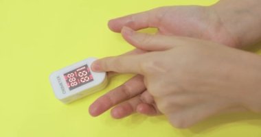 Kişi, nabız oksimetresi kullanarak oksijen doygunluğunu ölçüyor..