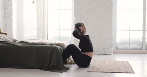 Urheilullinen nainen tekee abs harjoituksia crunches lattialla matolla kotona, sivunäkymä. — kuvapankkivideo