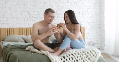 Sportif genç adam ve kadın evde çalıştıktan sonra birlikte hamburger yiyorlar..