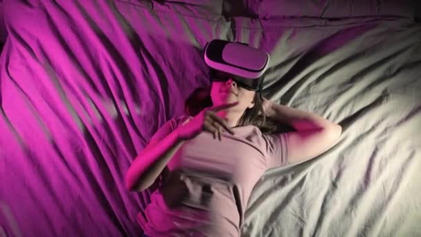 Frau liegt in Virtual-Reality-3D-Brille im Bett und wischt mit der Hand in der Luft. — Stockvideo