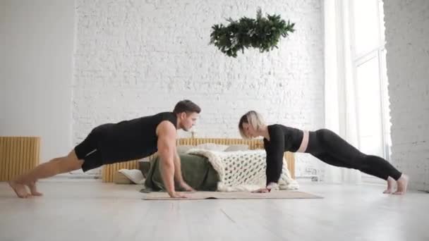 Man and woman doing push up exercises and giving each other high five at home. — Stock Video