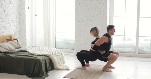 Fitness couple man and woman are doing squats exercises together at home. — Stock Video