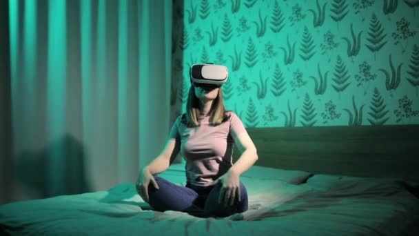 Mujer está sentada en la cama en realidad virtual gafas 3D y agitando las manos en el aire. — Vídeo de stock