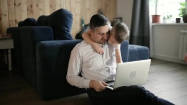 Baba ve oğul birlikte ev ödevi yapıyorlar. Laptop, uzaktan eğitim, tecrit..