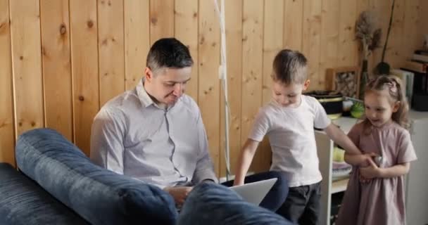 Pai está tentando trabalhar no laptop e crianças impedi-lo pressionando botões. — Vídeo de Stock
