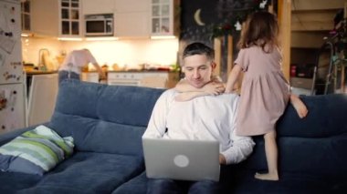 Babam laptopta çalışırken iki çocuk oturma odasında ona sarılıyor..