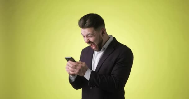 Worried young man in office suit looking on smartphone doing winner gesture. — Stock Video