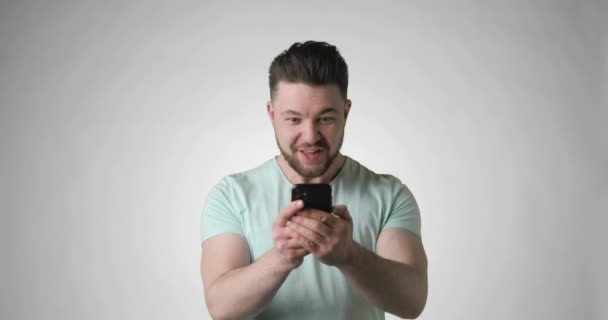 Hombre feliz en camiseta verde mirando en el teléfono inteligente gritando haciendo gesto ganador. — Vídeo de stock