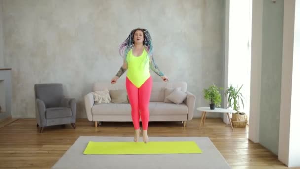 Fat woman in bright sportswear is jumping rope doing cardio at home, front view. — Stock Video