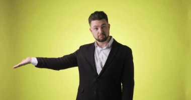 Ofisteki duygusal adam sarı arka plandaki boş avuca işaret ediyor..