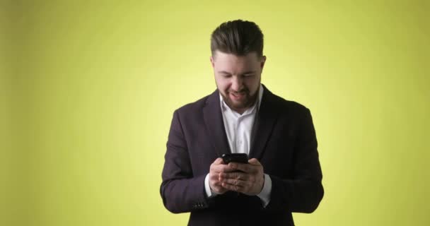 Feliz joven ganador en traje de oficina mira en el teléfono inteligente dice que sí, gritando. — Vídeo de stock