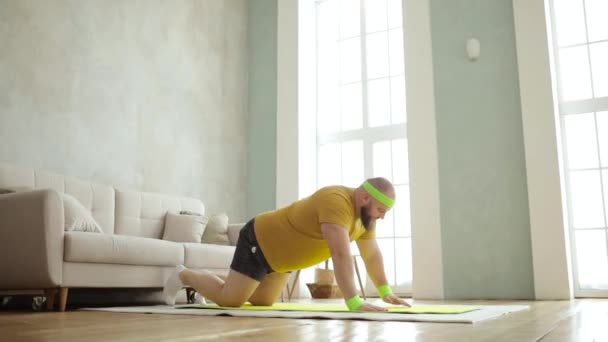Tlustý muž dělá sportovní push-ups cvičení stojící na kolenou na podložce doma.. — Stock video