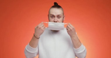 Sakallı adam maske takıyor ve kırmızı arka planda baş parmağını kaldırıyor..